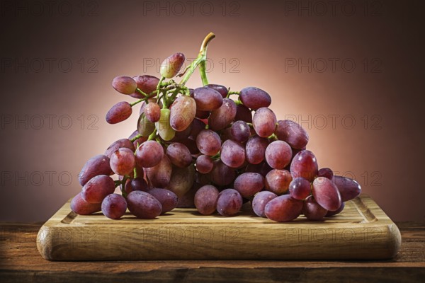 Rose grape on wooden cutting board and brown gradient background