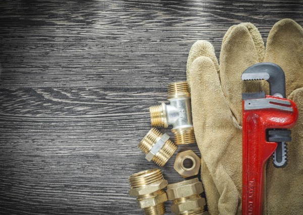 Plumbing pipe wrench fittings safety gloves on wooden board