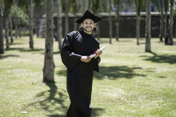 Portrait, student and happy man at graduation with certificate in university campus for success and achievement