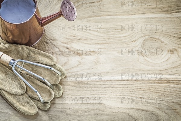 Watering can metal rake gardening gloves on wood board copy space agriculture concept