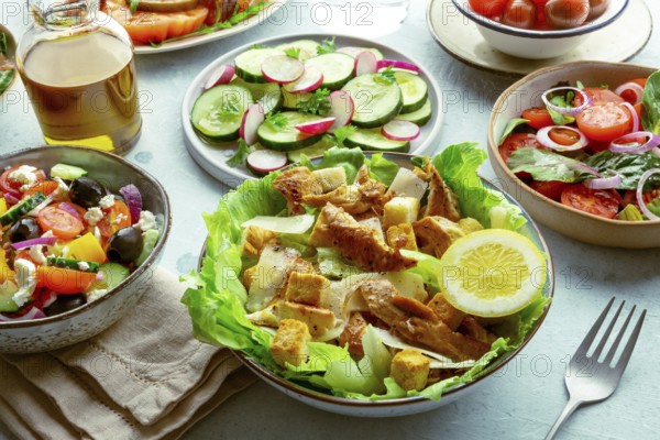 Fresh salads, an assortment. Variety of plates and bowls with green vegetables. Healthy food. Caesar salad with chicken, Greek salad etc, Food photography, Food photography