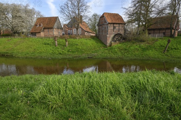 Traditional brick houses by a river, surrounded by green spring landscape, vreden, münsterland, germany