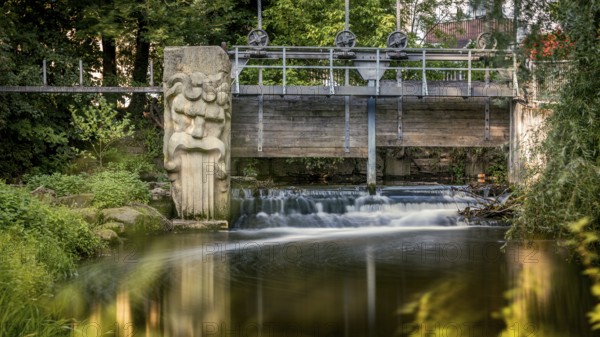Gundelsheim in Upper Franconia, stream, weir, small bridge with sculpture over a waterfall, embedded in lush green nature