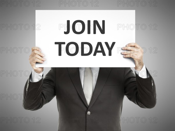 A business man holding a paper in front of his face with the text join today