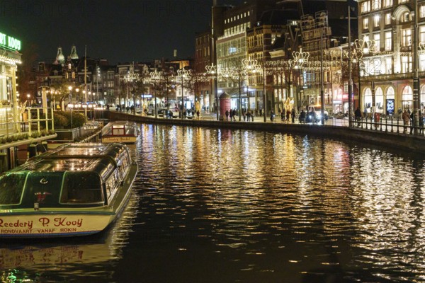 A night view of the canal with illuminated buildings and boats reflected in the water, Amsterdam, Netherlands
