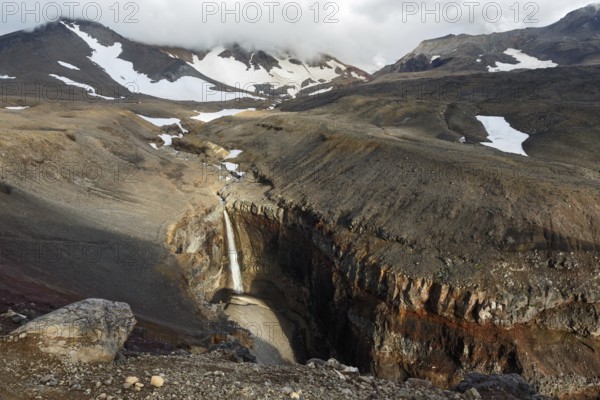 Beautiful landscape of Kamchatka Peninsula: view of Dangerous Canyon (Opasny Canyon), picturesque waterfall on the river Vulkannaya under the active Mutnovsky Volcano. Kamchatka, Far East, Russia, Europe