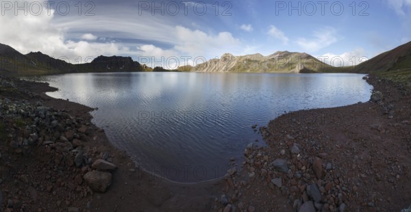 Panorama mountain landscape of Kamchatka Peninsula: beautiful summer view of crater lake of Khangar Volcano on sunny day at sunrise. Eurasia, Russian Far East, Kamchatka Region