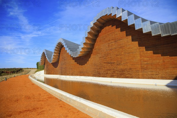 Wave-shaped winery roof. Fragment of the facade is reflected in the pool. Winery - bodega Bodegas Ysios. Journey to the warm Spanish autumn. The sunset