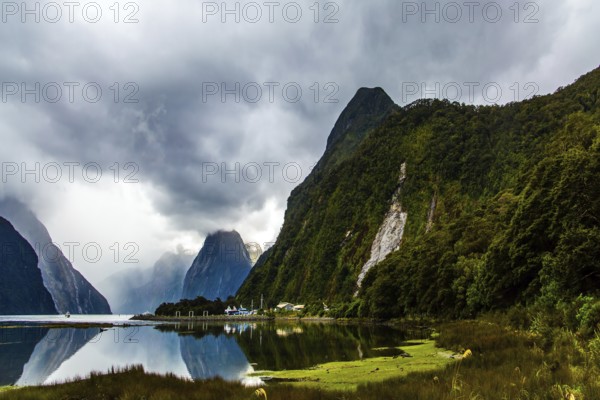 New Zealand. Storm clouds cover the sky over the famous ocean fjord Milford Sound. Port of tourist ships, yachts and boats. Concept of ecological, active and photographic tourism