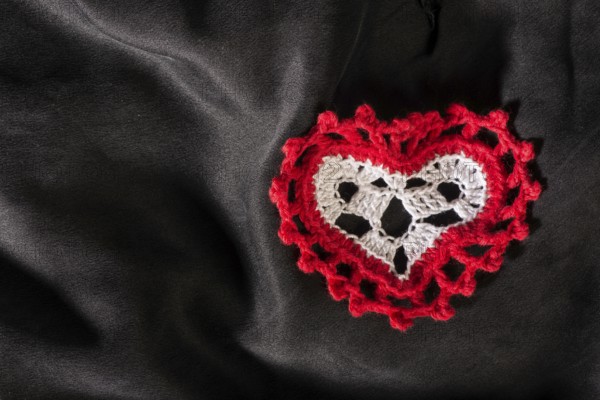 Heart shape made of red textile on black satin