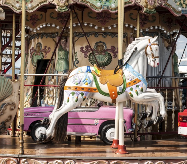Children's vintage amusement park. White horses on children's carousel