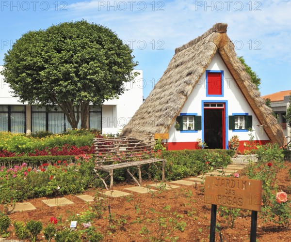 Old house-museum of the first settlers on the island of Madeira. Charming white cottage with a thatched roof and gable small garden with flowers