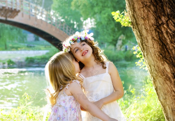 Kid girls playing in spring outdoor river park whispering ear