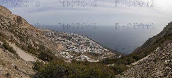 View down to serpentine road and Kamari at the lava beach, in the sea the island Anafi, panoramic view, island Santorini, Cyclades, Greece, Europe