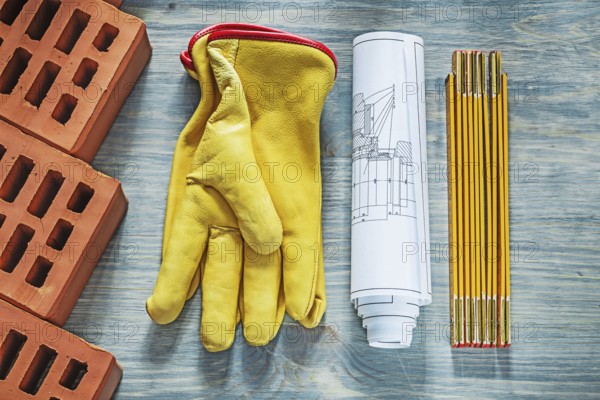 Red bricks leather safety gloves wooden meter construction drawings building concept