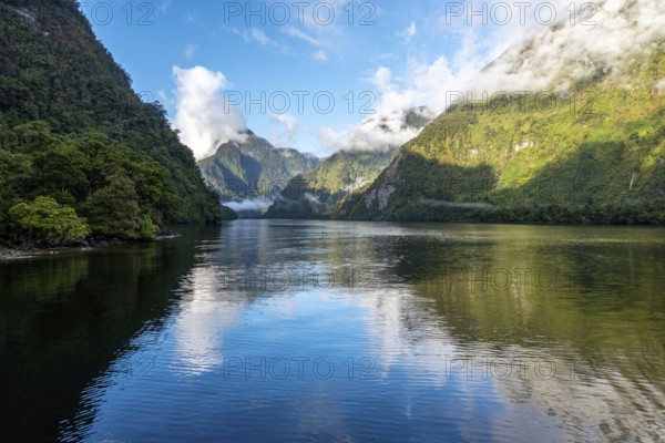 A new morning dawning at Doutful Sound, clouds hanging low in the mountains, South Island of New Zealand
