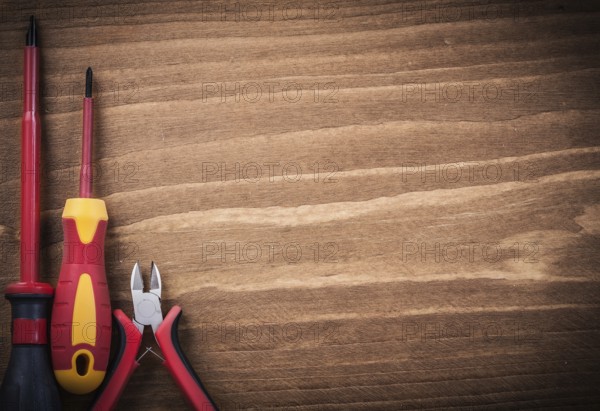 Sharp nippers insulated screwdrivers on wooden board copyspace electricity concept