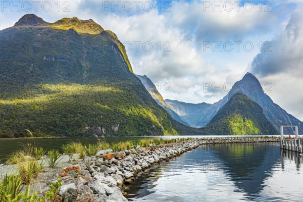 The mountains are reflected in the smooth water of the fjord. The most famous and picturesque fjord is Milford Soun. Fiordland park. New Zealand. South Island