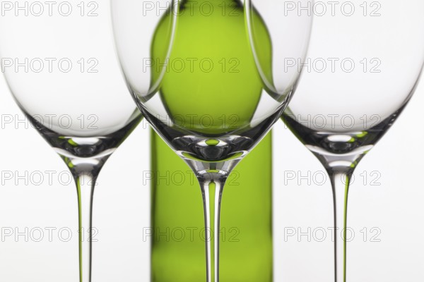 Three empty glasses of wine and green bottle on the white background