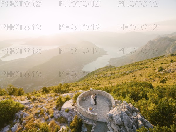 Bride and groom standing on the observation deck on the mountain against the backdrop of the Bay of Kotor.