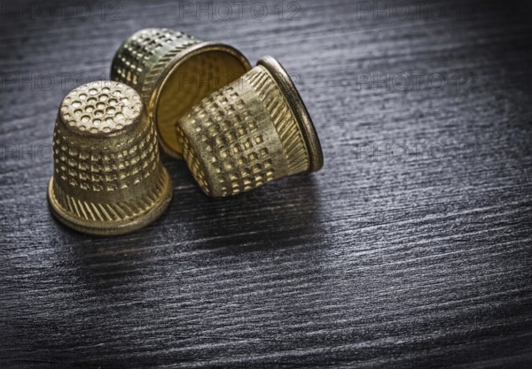 Metal thimbles on wooden board fancy-work concept