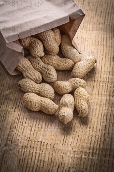 Peanuts poured from paper bag on wooden board food and drink still life