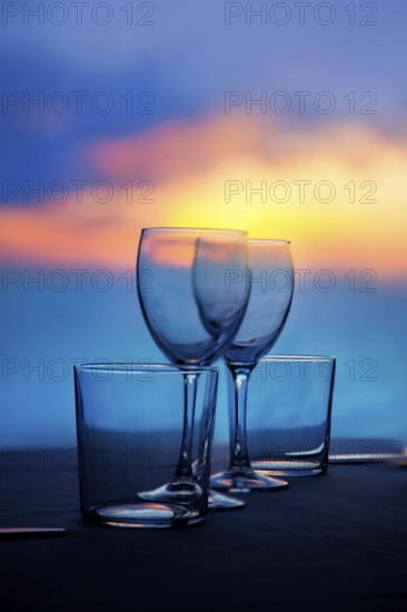 Dish of cups and crystal transparent glasses on a sea sunset table