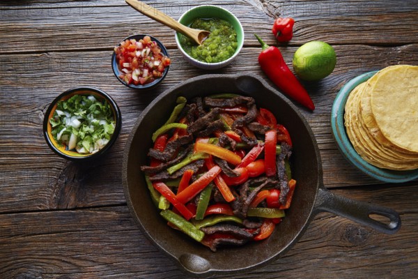 Beef fajitas in a pan with sauces chili and sides Mexican food