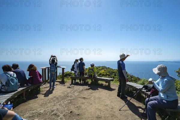 A group of people stand on a viewing platform on Mount Nokogiri in Chiba and look out over the sea towards Tokyo