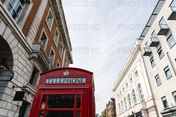 Traditional red telephone box in London, England, UK. Low angle view against sky in Covent Garden area