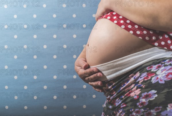 Pregnant woman shows his belly. Blue background