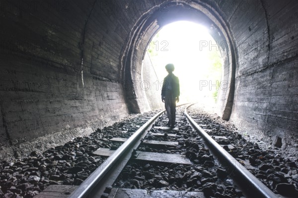 Child walking in railway tunnel. Vintage clothes