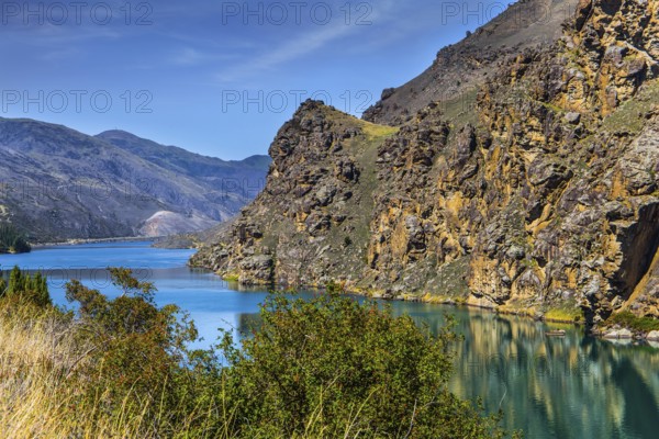 The picturesque lake Dunstan near the town of Cromwell. Emerald-colored quiet deep lake water and green grassy lawns. New Zealand, South Island. The concept of ecological and photo tourism