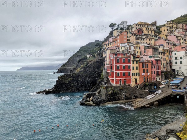 A picturesque seaside village with vibrant houses on cliffs beside a choppy ocean. Cinque Terre, Italy, Europe