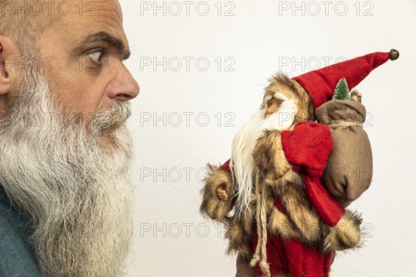 An image of a bearded man looking to a Santa Claus puppet