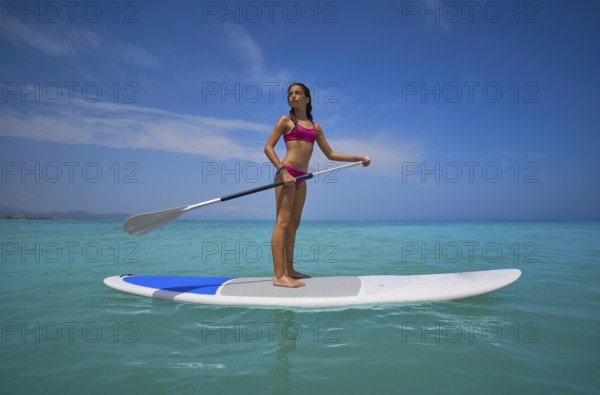 Girl standing on paddle surf board SUP in summer