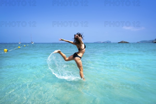 Ibiza beach girl splashing water jump in Balearic islands
