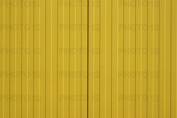 The close-up of a colourful and bright yellow corrugated metal wall of a shopping centre