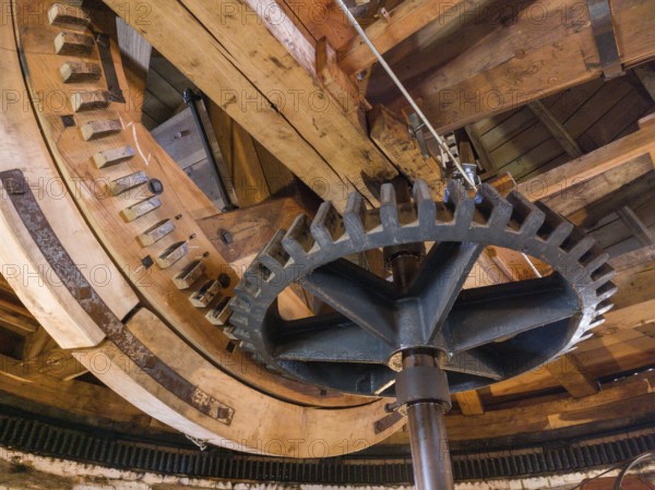 Large cogwheels within an old wooden structure, industrial mechanics visible