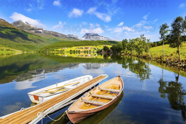 Summer trip to Norway. The lovely and calm lake Eidsvatnet. Several boats are tied up near the shore of the lake. Warm sunny day in July. Northern Europe