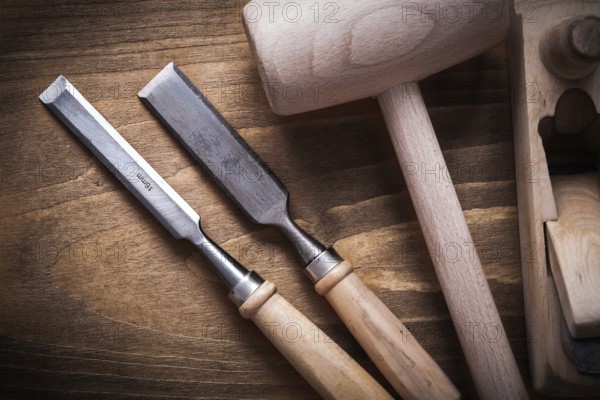 Wooden hammer shaving plane flat chisels on wood board top view construction concept