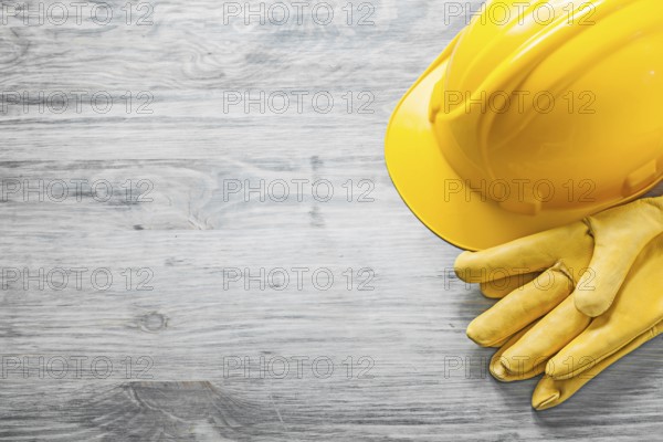 Yellow hard hat protective gloves on wooden board copy space construction concept