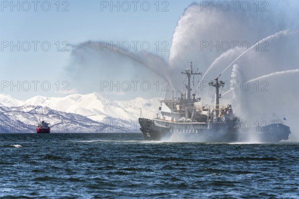 KAMCHATKA, RUSSIA, APR 27, 2019: Firefighting and rescue ship of Pacific Fleet of Russia spraying water on ocean for supporting emergency case of fire of warships, cargo ships, oil and gas industry