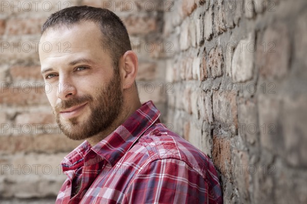 An image of a bearded man at the brick wall