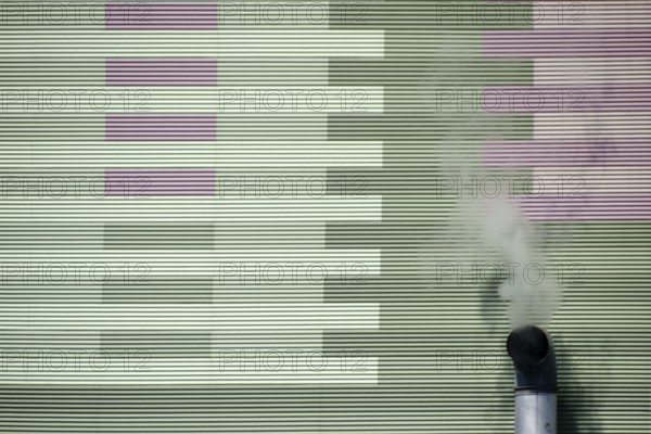 The smoking chimney of an industrial plant on the outer wall of a power station