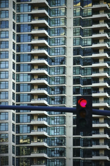 A multi-storey apartment building and tower block with symmetrically arranged balconies and a traffic light in front of the façade