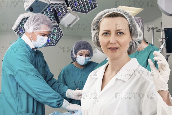 Adult female anesthetist with syringe on the surgery teem background