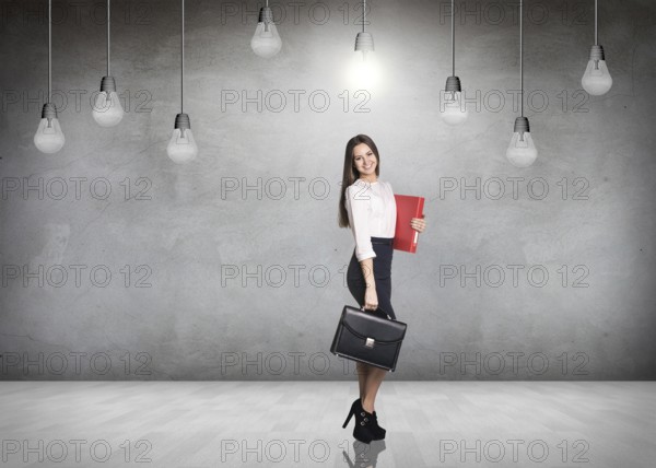 Business woman stnads in a gray room with hanging bulbs