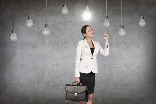 Business woman stands in a gray room with hanging bulbs