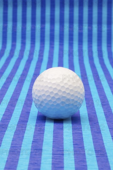 White golf ball on blue striped tablecloth